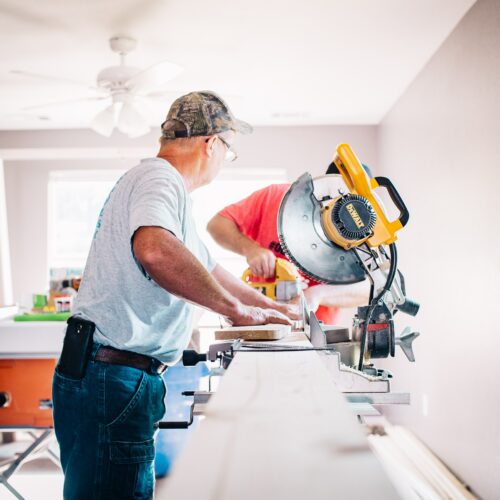 Man sliding a piece of wood across a table saw.