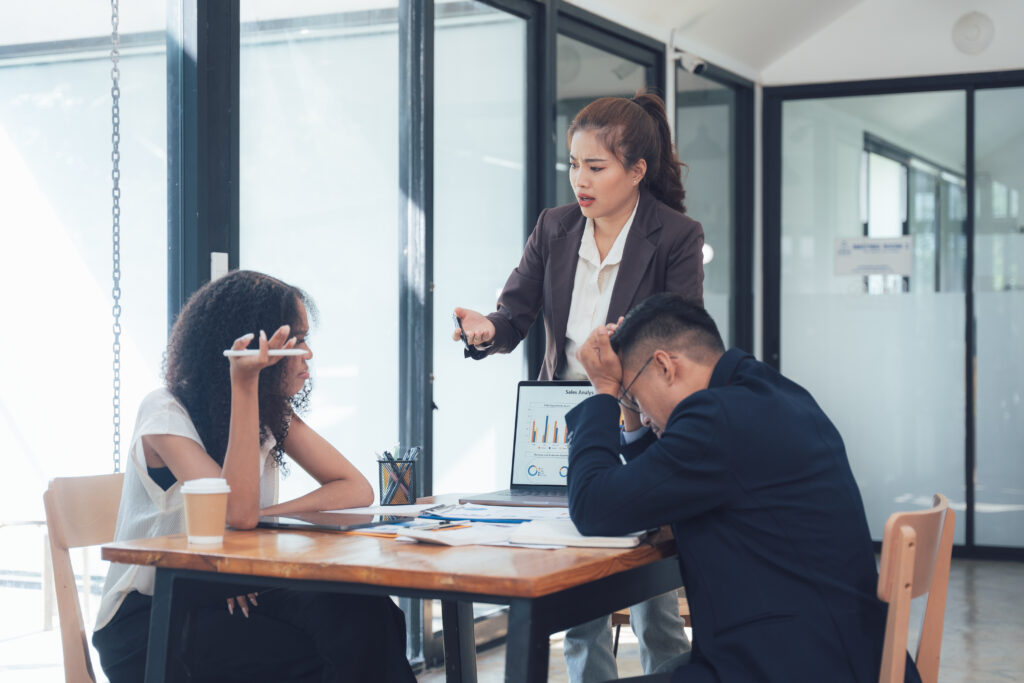 Frustrated manager confronting a stressed team in a corporate setting, illustrating situations where professional liability insurance may be crucial.