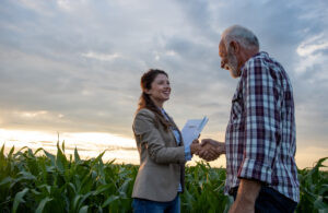Farm Owners Insurance consultation showing a senior farmer shaking hands with an insurance agent in a corn field